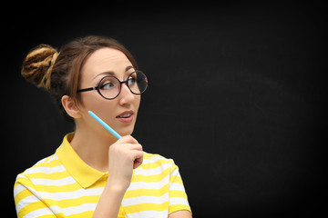 Obraz premium Attractive young blond girl in glasses against blackboard.