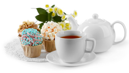 Cup of tea with tasty cupcakes and teapot, isolated on white