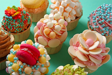 Tasty cupcakes with original decoration on turquoise background