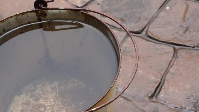 rain drop inside full water of rusty old bucket on wet floor