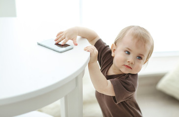Baby trying to take smartphone from the table