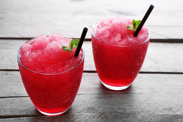 Glasses of cherry soda with crushed ice and fresh mint on rustic wooden background