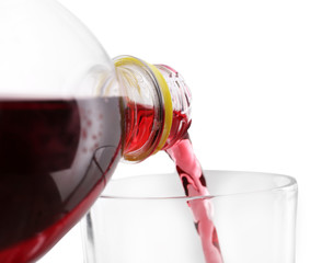 Pouring cherry soda from plastic bottle into glass on grey background