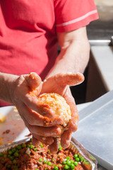 The making of sicilian arancini: cook modelling a rice arancino filled with italian ragu in a typical cone shape