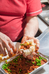 The making of sicilian arancini: cook modelling a rice arancino filled with italian ragu in a typical cone shape