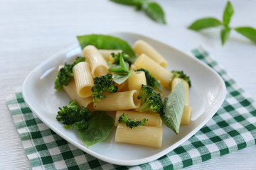 Boiled rigatoni pasta with broccoli and basil on white plate