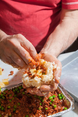 The making of sicilian arancini: cook modelling a rice arancino filled with italian ragu in a typical cone shape