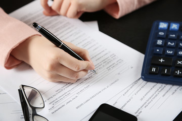 Fototapeta premium Female hand signing document at the desk closeup