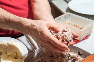 The making of sicilian arancini: cook modelling a rice arancino filled with italian ragu in a typical cone shape