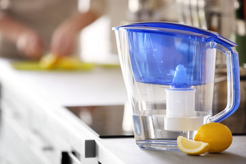 Water filter jug with lemon on kitchen table