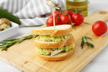 Vegetarian avocado sandwich on a wooden board.