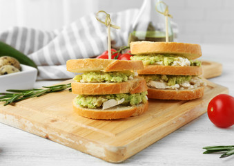 Vegetarian avocado sandwiches on a wooden board.