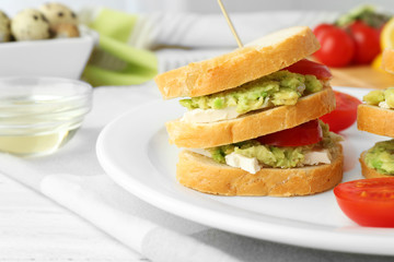 Vegetarian avocado sandwich on a white plate.