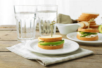 Vegetarian avocado sandwiches on white plate.