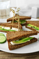 Vegetarian avocado sandwich with dark rye bread on a white plate