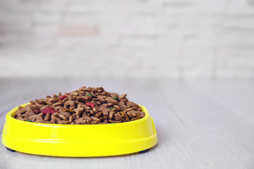Bowl with dog food on the floor in front of brick wall background