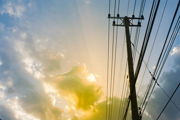 Silhouette, Pole with power lines lies across. The light shines in the evening sky backdrop, with space.