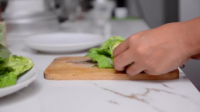 Close up and dolly slider shot woman hand cutting green vegetable on white table HD 1920x1080