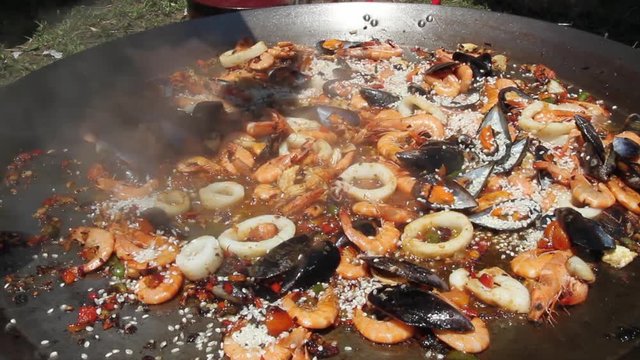 Echando arroz  al sofrito de verduras y marisco para la preparacion de una paella ( 3 Cortes con continuidad )
