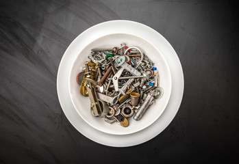 piatto da cucina pieno di minuteria metallica su fondo nero ardesia