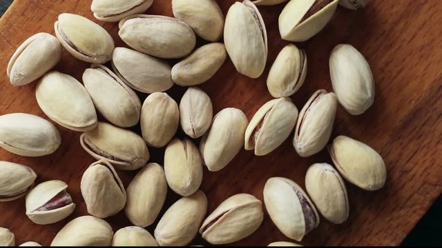 Pistachios on wooden background. Dark and moody style. Magic moon and mistic light. Top view with rotation 360