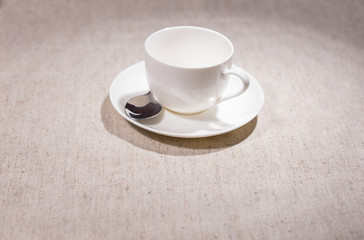 Single teacup and saucer with spoon over gray