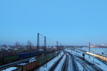 Fototapeta premium Freight trains with carriages stand on railways at snowy winter
