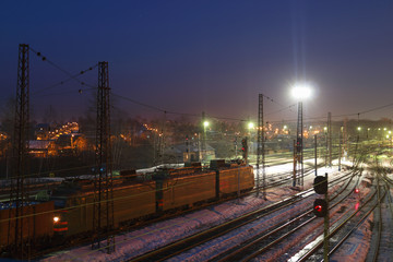 Freight train with carriages move on railways at winter night
