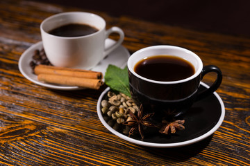 Black cup of tea in focus with coffee behind it