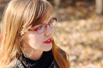 Young smiling woman in glasses looks away at sunny day