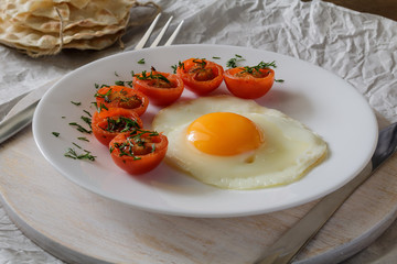 Breakfast made from fried egg, fried cherry tomatoes and bread.