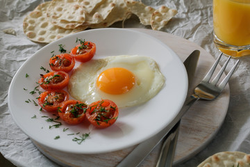 Breakfast made from fried egg, fried cherry tomatoes and bread.
