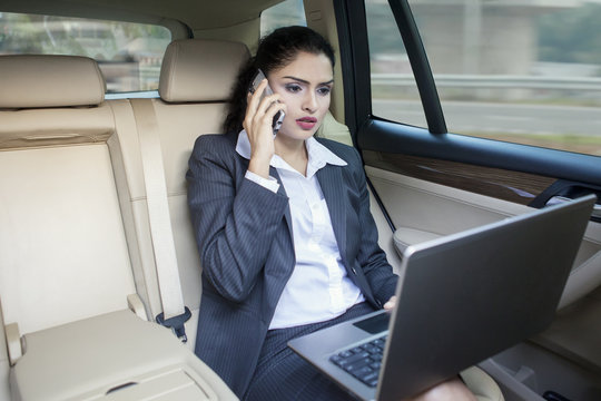 Busy Indian businesswoman working in car