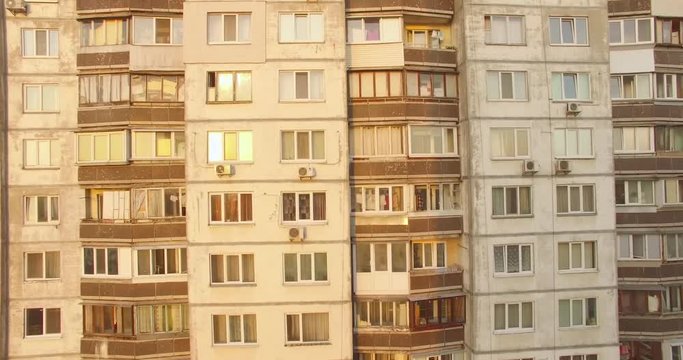 Aerial establishing shot of high rise building in dormitory area at sunrise. Flying from wide angle view to extreme close up