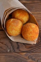 Arancini balls. Fried rice balls in paper on vintage wooden table. Snack. Close-up