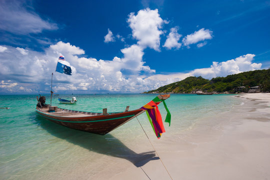 Picture of long tail boat on tropical beach. Ko li pe island. Clear water and blue sky with clouds. Horizontal