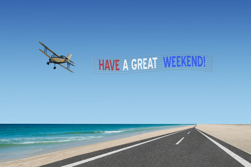 have a great weekend plane banner in american flag colors of red white and blue flying over road at beach - obrazy, fototapety, plakaty