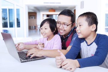Two kids using laptop with dad at home