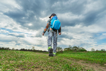 Naklejka na ściany i meble Little boy with backpack walking in nature. Travel concept.