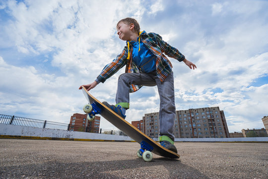 Happy small boy is going to skateboarding - people, sport and skateboarding concept.