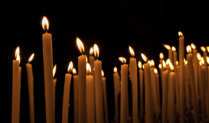 Lit yellow candles on a dark background