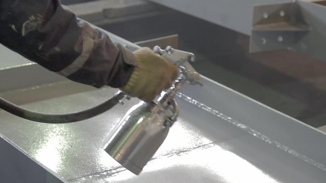 hand of worker is painting a metal beams