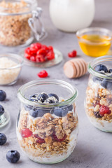 Glass jars of oat flakes with fruit, yogurt and honey.