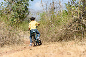 Fototapeta premium Little boy ride bicycle on the rock road.