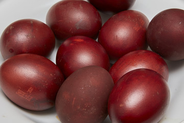 Colorful Easter eggs in a white plate on old wooden table backgr