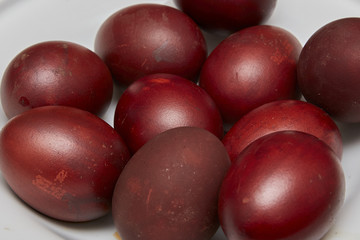 Colorful Easter eggs in a white plate on old wooden table backgr
