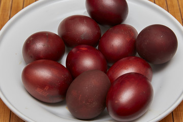 Colorful Easter eggs in a white plate on old wooden table backgr