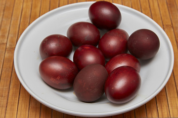 Colorful Easter eggs in a white plate on old wooden table backgr