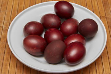 Colorful Easter eggs in a white plate on old wooden table backgr