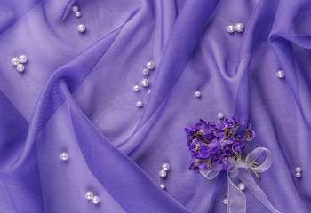 pearls  and bouquet of violets on the blue fabric